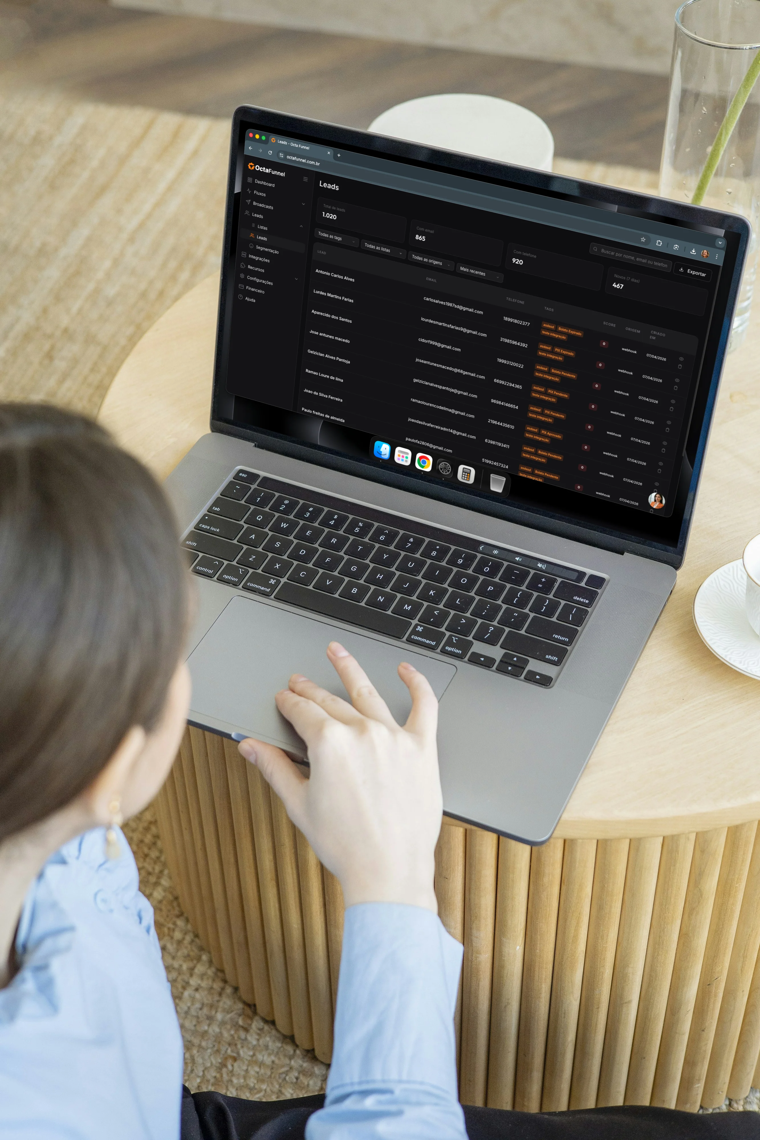 Mulher em cafeteria com laptop revisando leads da Octa Funnel