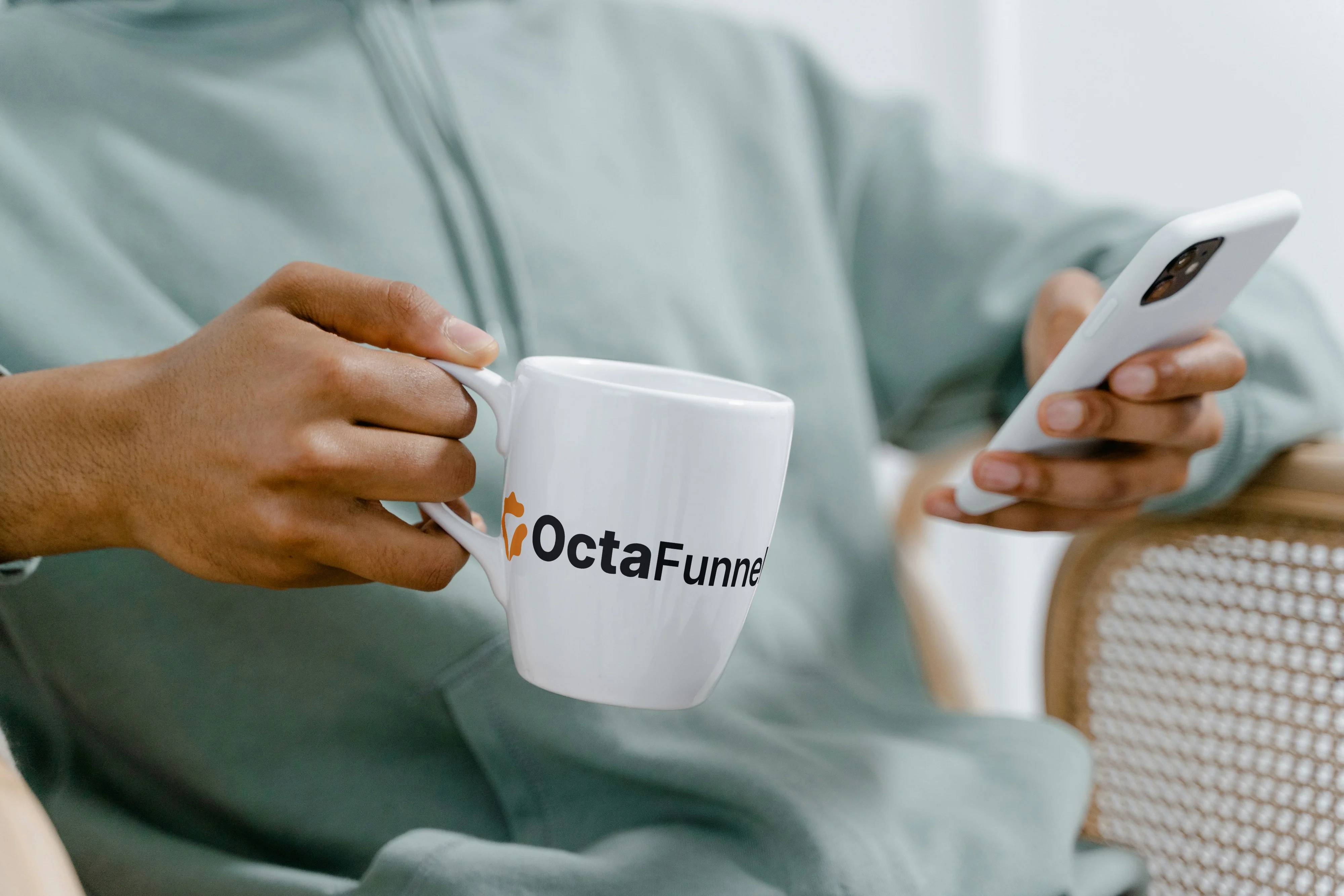 Homem de moletom da Octa Funnel com caneca e celular conferindo mensagens