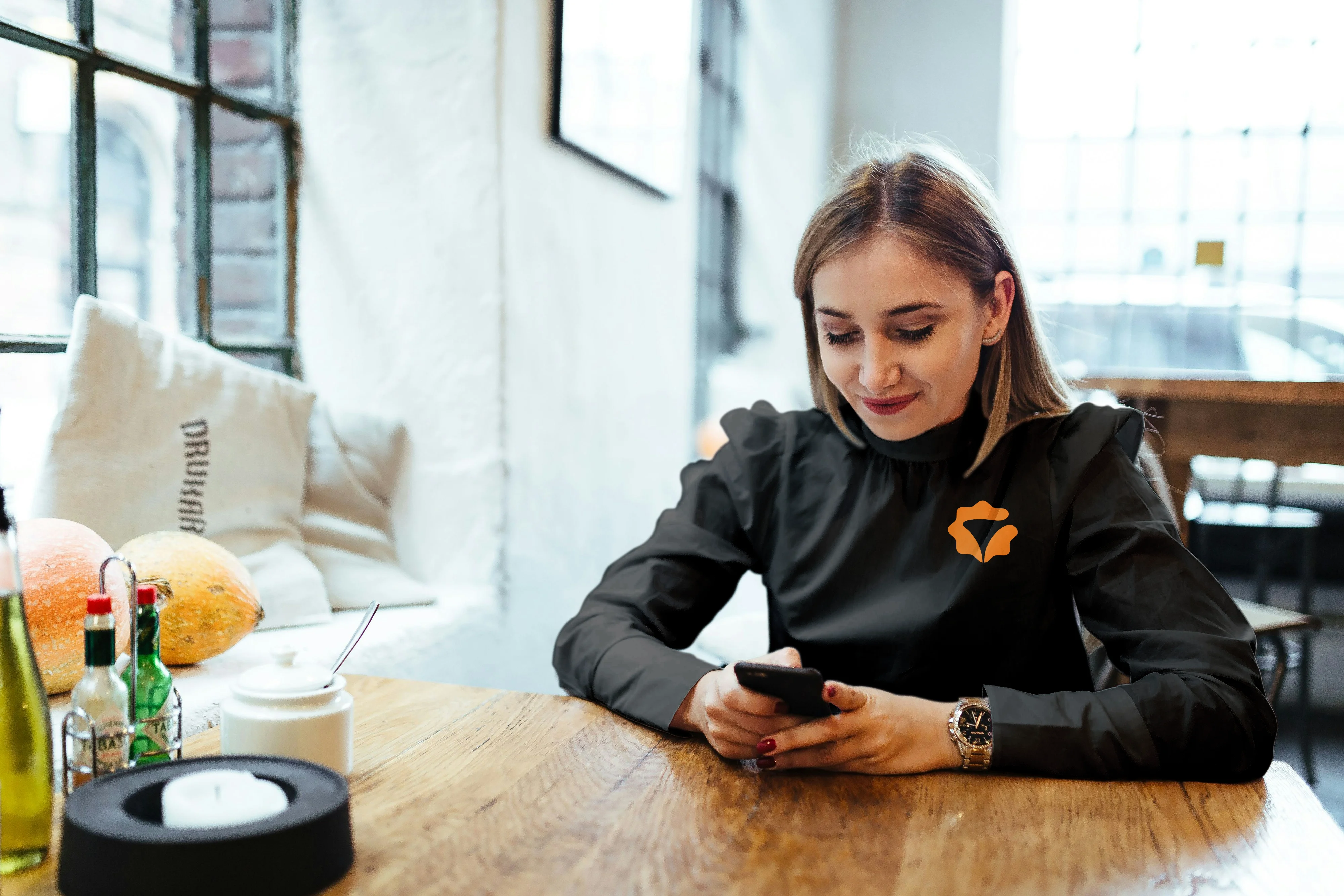 Mulher em café com camiseta da Octa Funnel lendo no celular