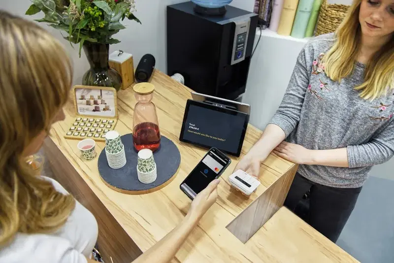 Mulher fazendo pagamento contactless em café com smartphone