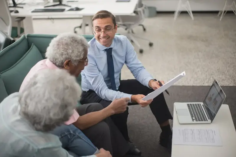 Consultant discussing financial plans with senior clients in a modern office setting, using document