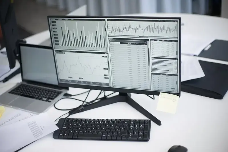 A professional workspace featuring computers and analytical graphs on a monitor, symbolizing modern 